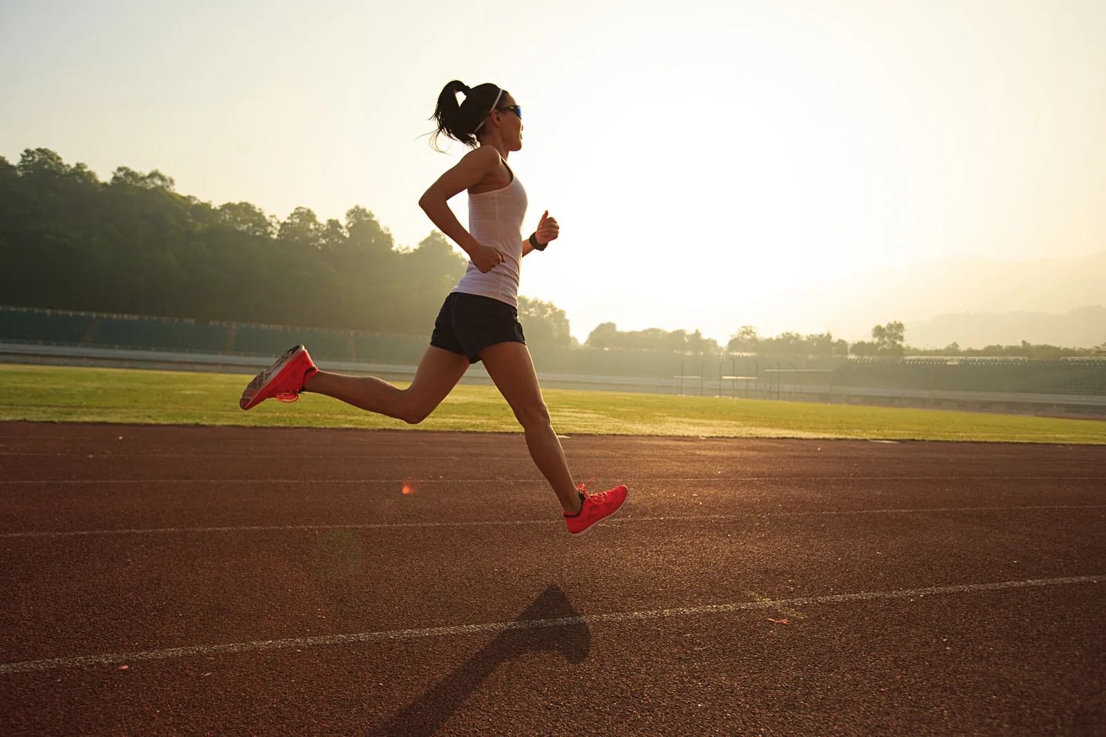 Woman sprinting on a track at sunrise